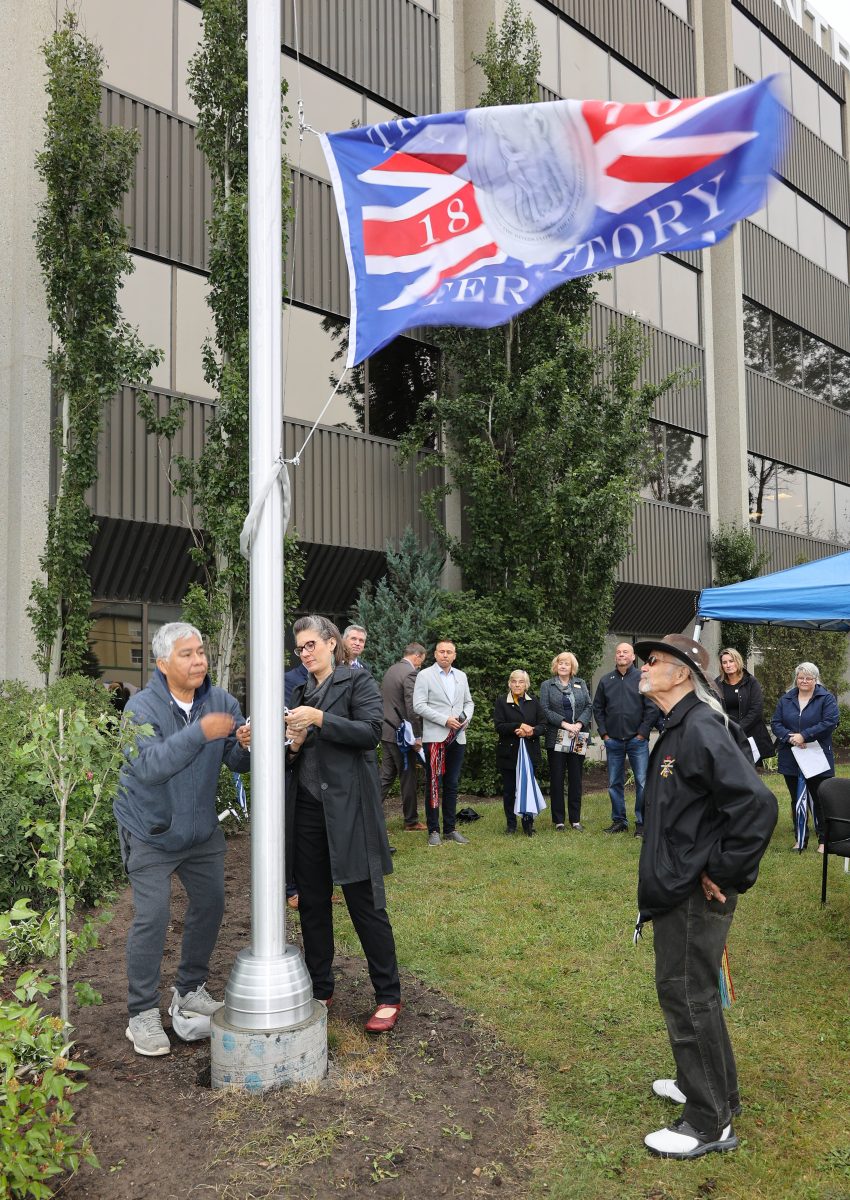 Elder-Cliff-Cardinal-and-Devonna-raise-Treaty-6-flag-850x1200